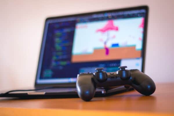 Black laptop computer beside controller on brown wooden surface