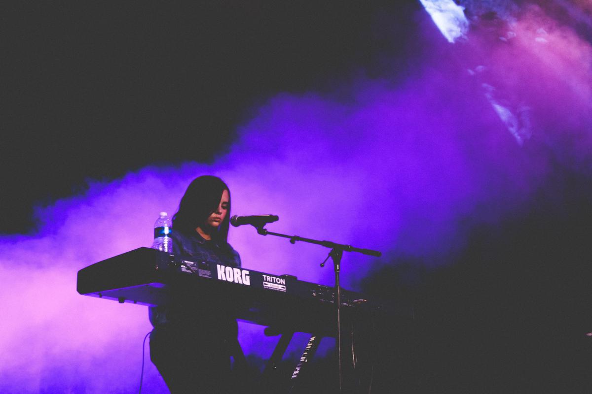 A person playing a 15-key portable keyboard with focused concentration.